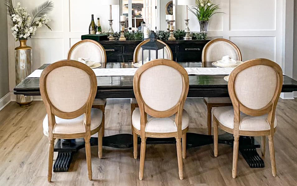 A dining room tables viewed from the side with three chairs with circular backs on each side of the table.