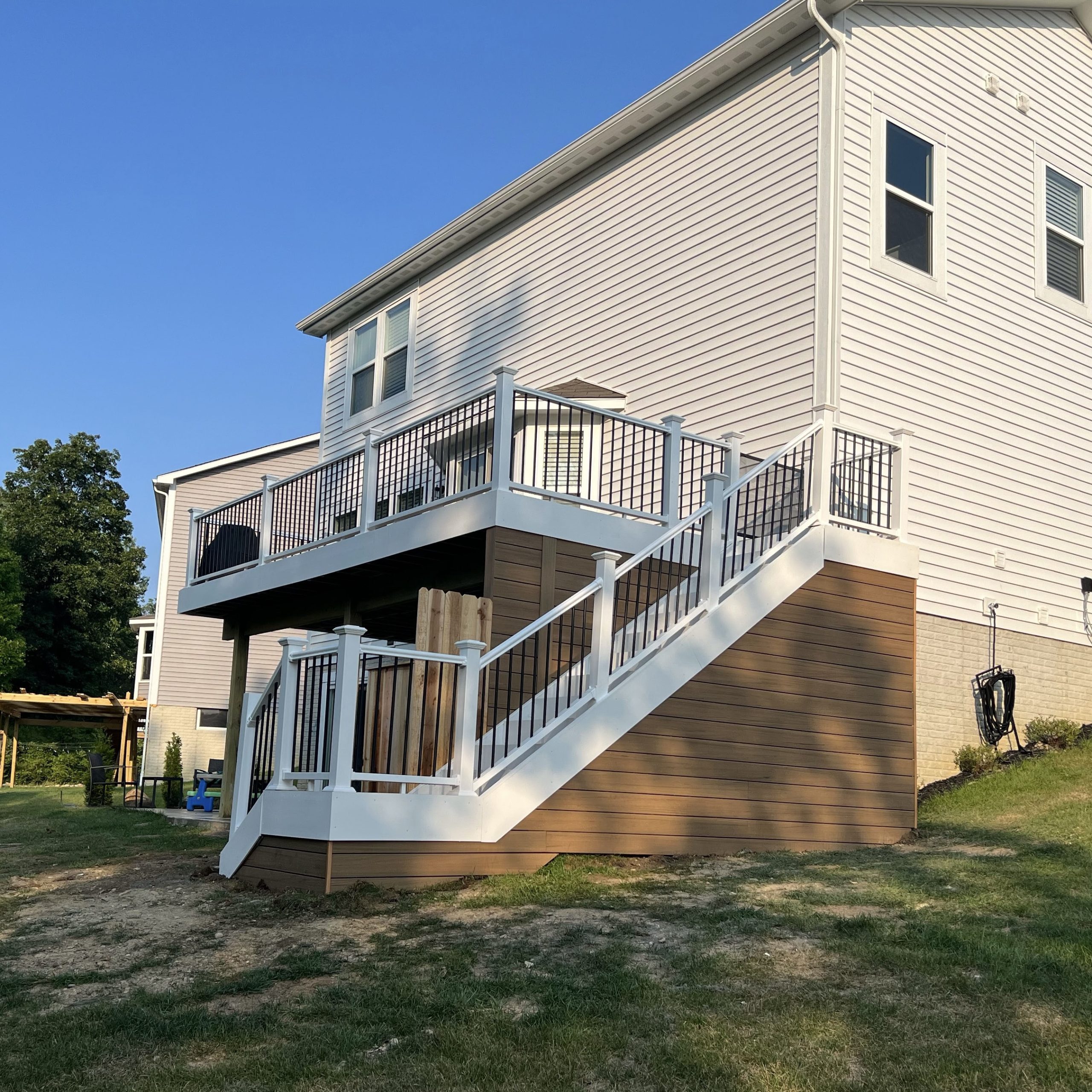 A deck that comes off the back of a home from the second story. The deck has stairs leading down to the backyard.